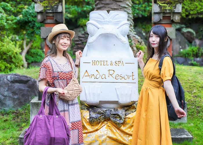 画像:カエル石像の前で写真を撮る2人の女性
